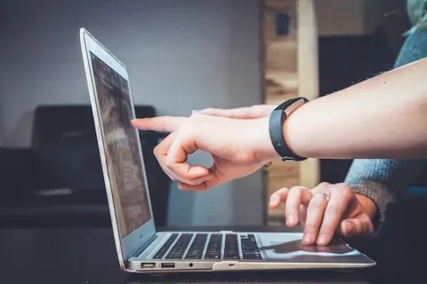 Two people pointing at a laptop screen during a discussion