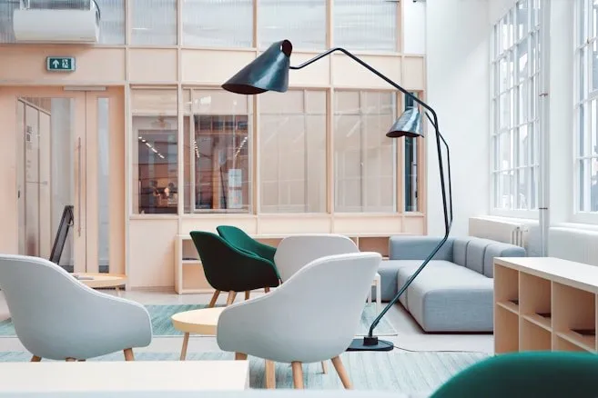 A bright, quiet office lounge with armchairs and tall windows