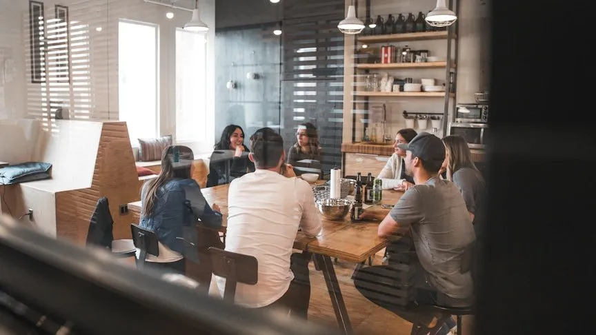 A group of colleagues talking around a table in a bright café-style office