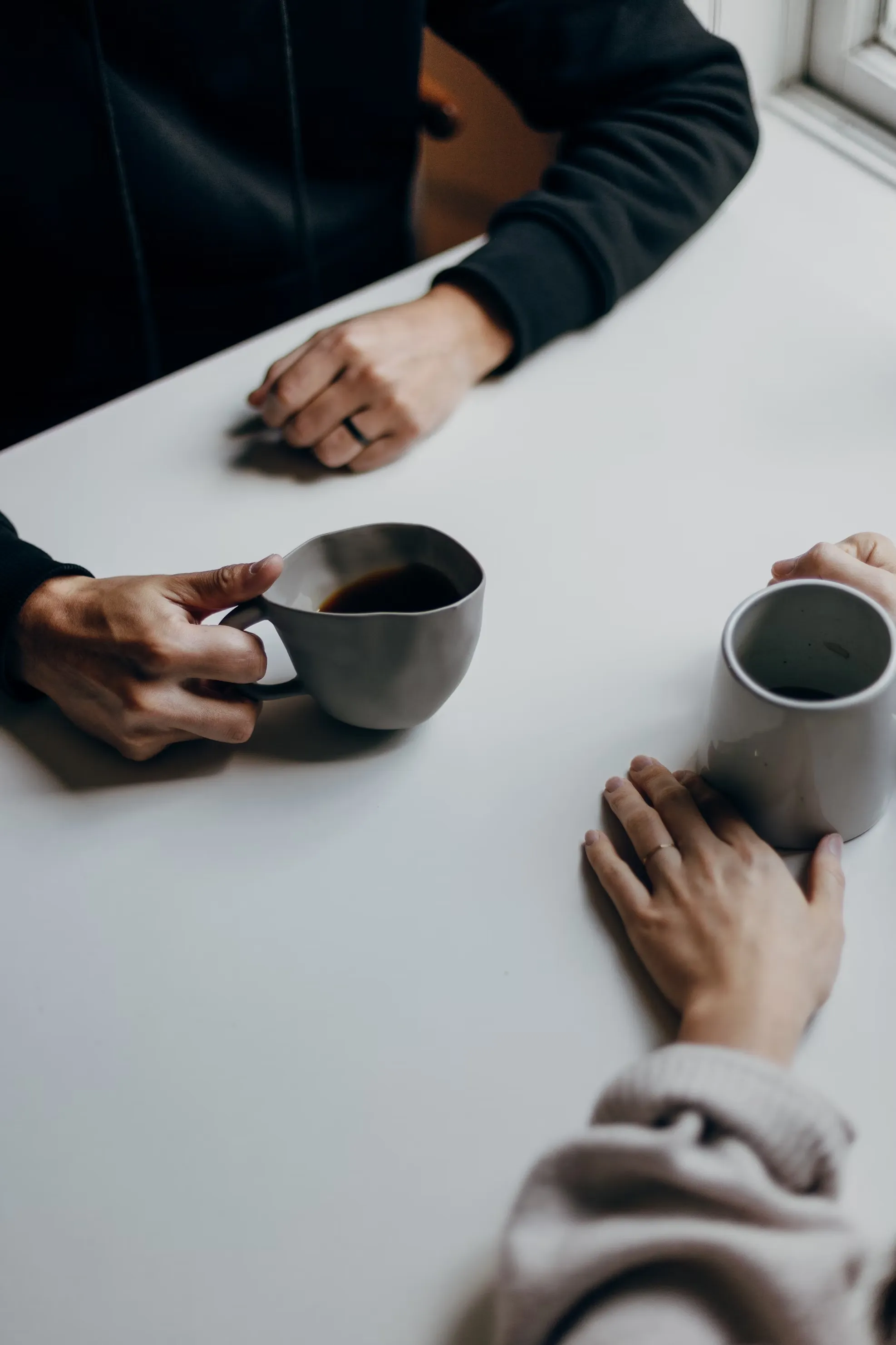 Two people talking over coffee at a white table