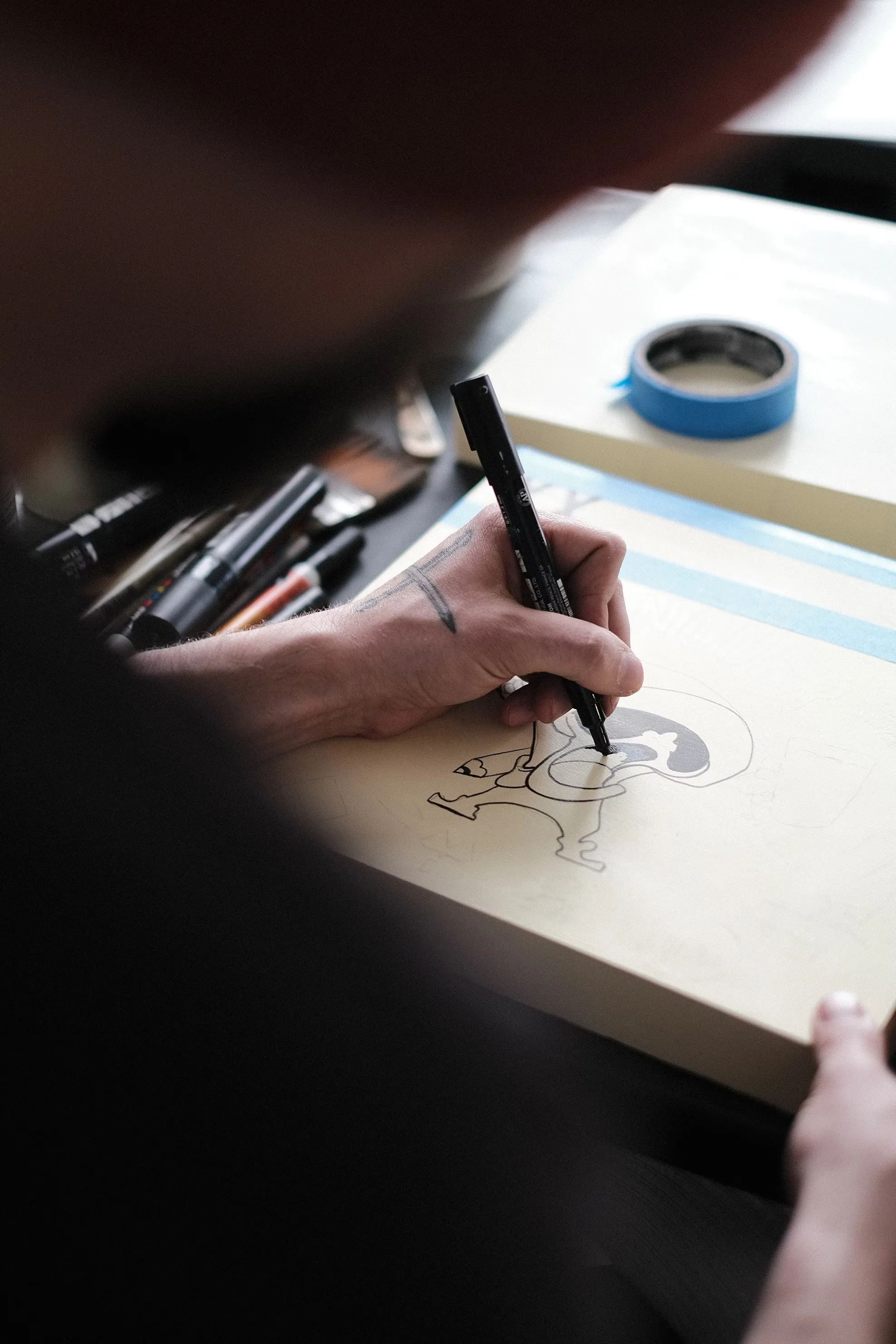 An artist sketching a drawing with a marker